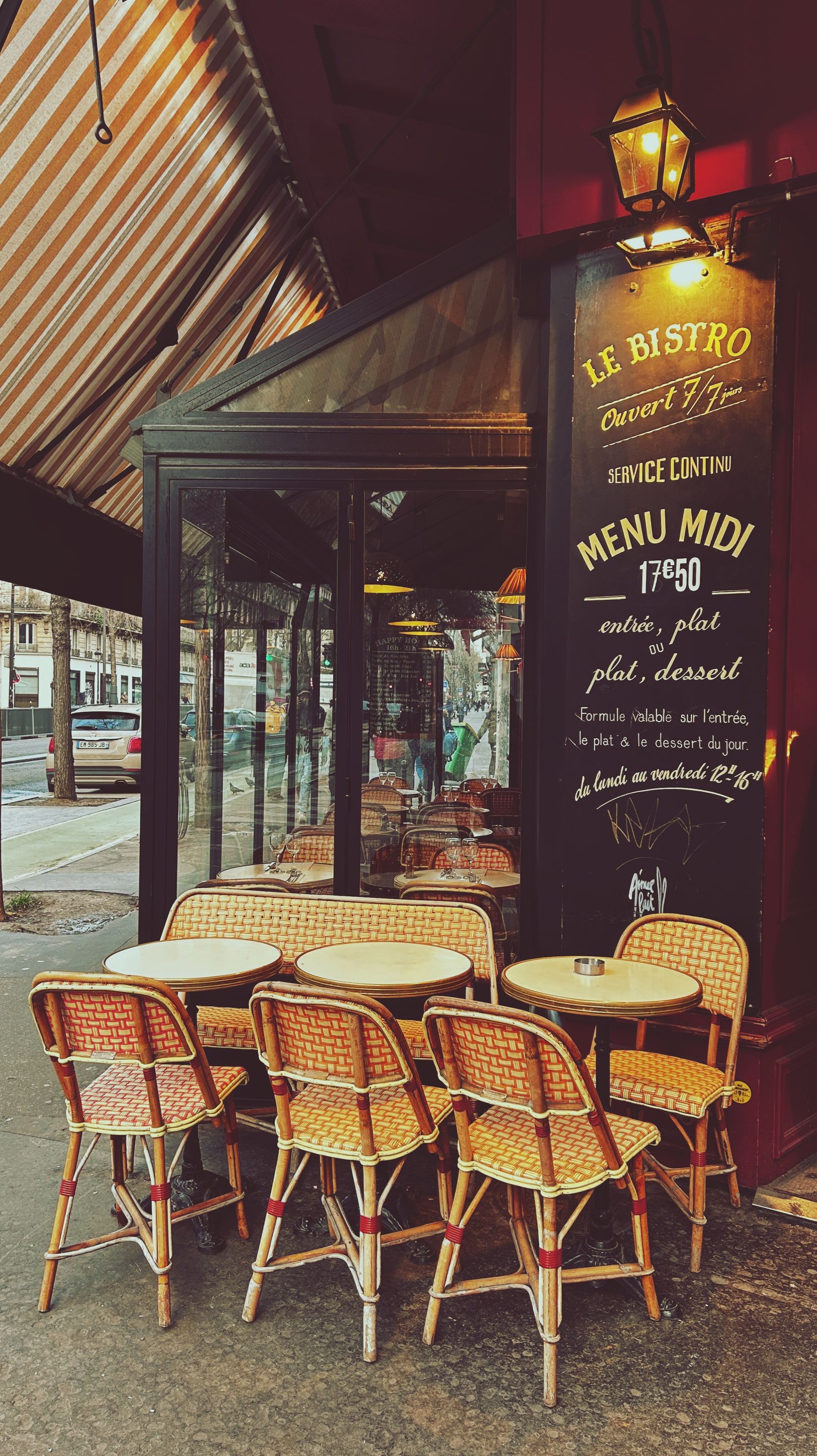 A charming Parisian bistro entrance with a handwritten chalkboard menu and café seating.